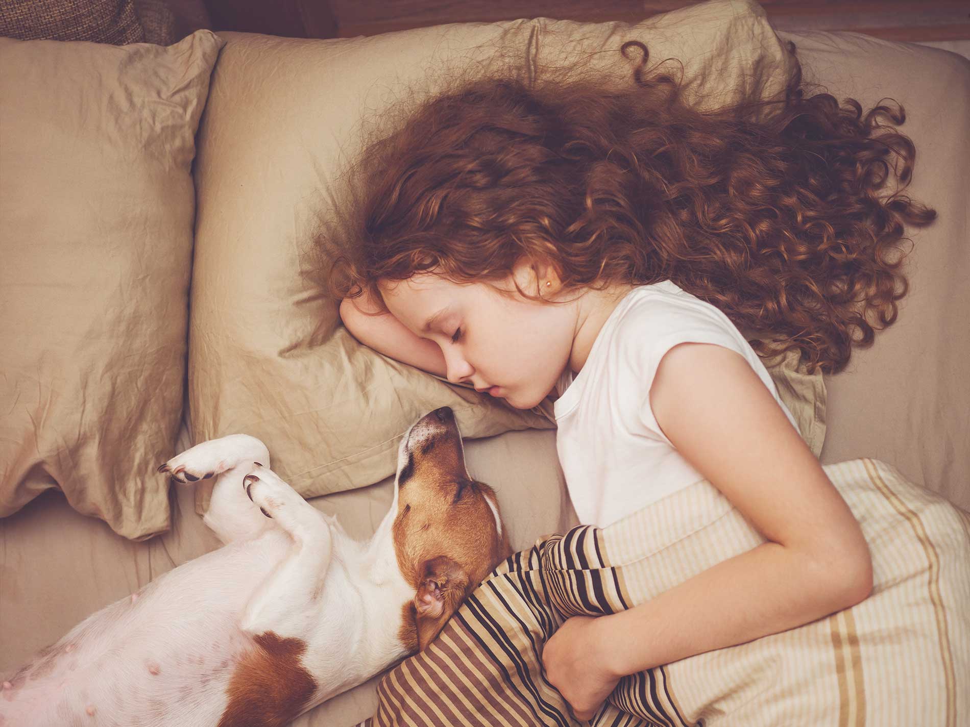 girl laying beside her dog on the bed