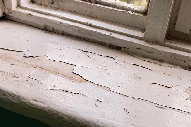 Window sill of an old house with peeling paint damage