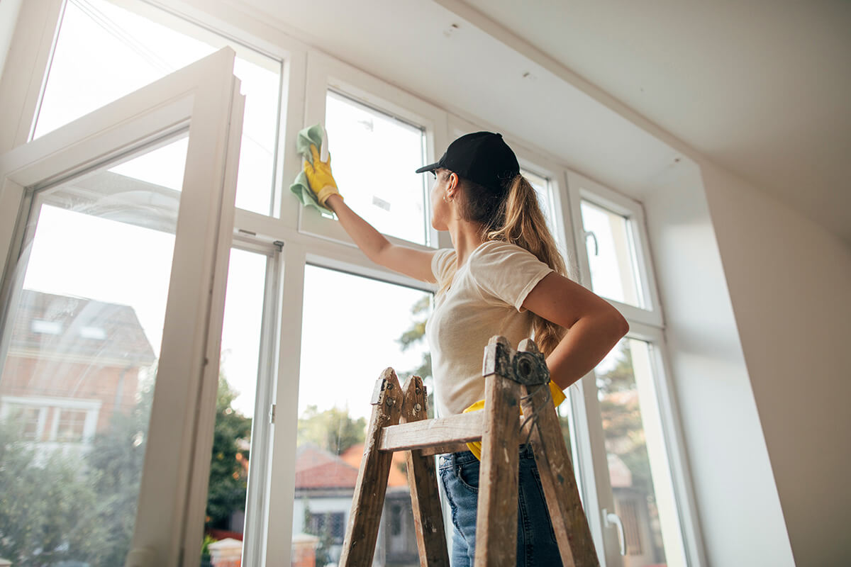 woman on a ladder cleaning window